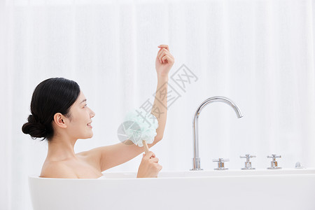 沐浴刷女性躺在浴缸手拿浴球刷洗澡背景