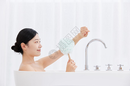 女性躺在浴缸手拿浴球刷洗澡图片