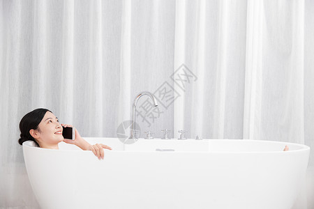 年轻女性洗泡泡浴接电话图片