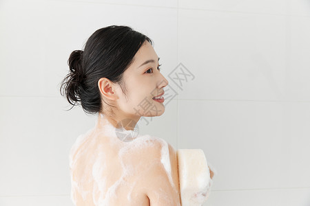 年轻女性使用沐浴球洗澡淋浴背景图片