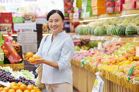 格林阿姨水果店内中年妇女挑选橘子背景