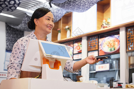 商店门前介绍牌面馆中年女收银员向顾客递取餐牌背景