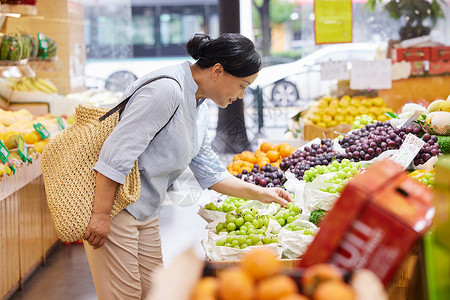 超市老人中年女性水果店内挑选水果背景