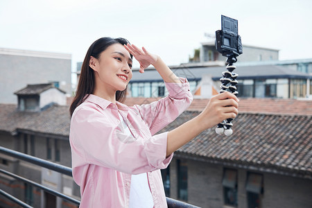 女视频博主拿相机户外拍摄背景图片