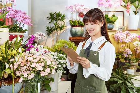 鲜花店美女销售员拿笔纸记录图片