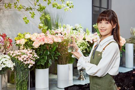 浇花水壶花店美女服务员拿水壶浇花背景