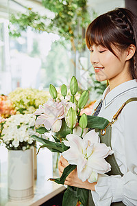 鲜花店美女销售员手捧百合花图片