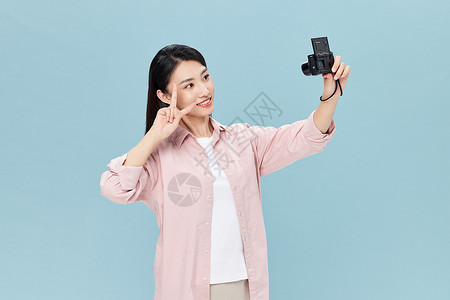 年轻女性手拿相机自拍图片