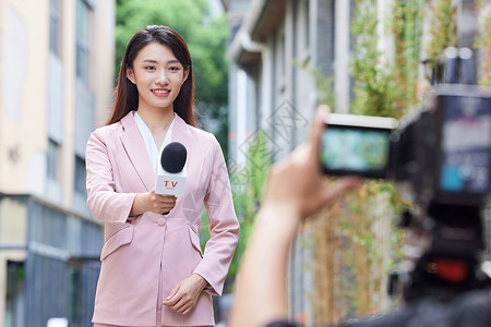 户外访问手拿话筒的青年女记者户外采访背景