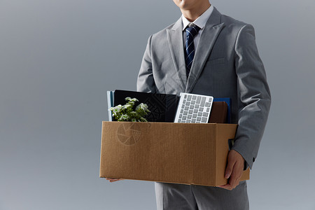 失业商务男性被开除抱着纸箱商务男性被开除抱着办公用品纸箱特写背景