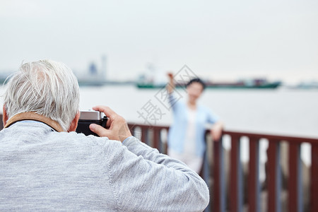 海边照爷爷给奶娘拍游客照背景