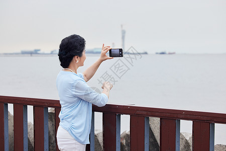 金婚照片素材奶奶拿着手机对海边拍风景背景