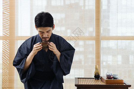 日系男性手拿茶筅筛茶特写日系男性手拿茶碗喝茶背景