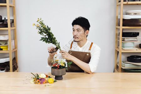 花艺工作室男性花艺师修剪花枝背景