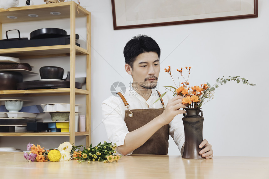 年轻男花艺师插花调整花枝图片