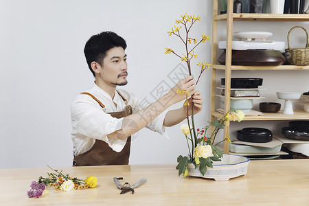 年轻男花艺师插花调整花枝图片