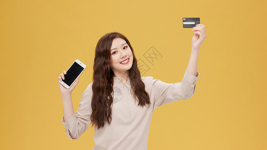 青年女性手拿信用卡和手机图片