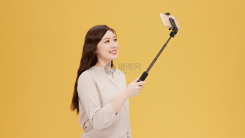青年女性使用自拍杆手机直播图片
