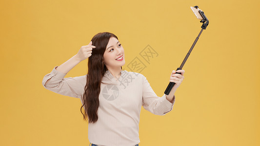使用相机拍照的韩系女孩青年女性使用自拍杆手机直播背景