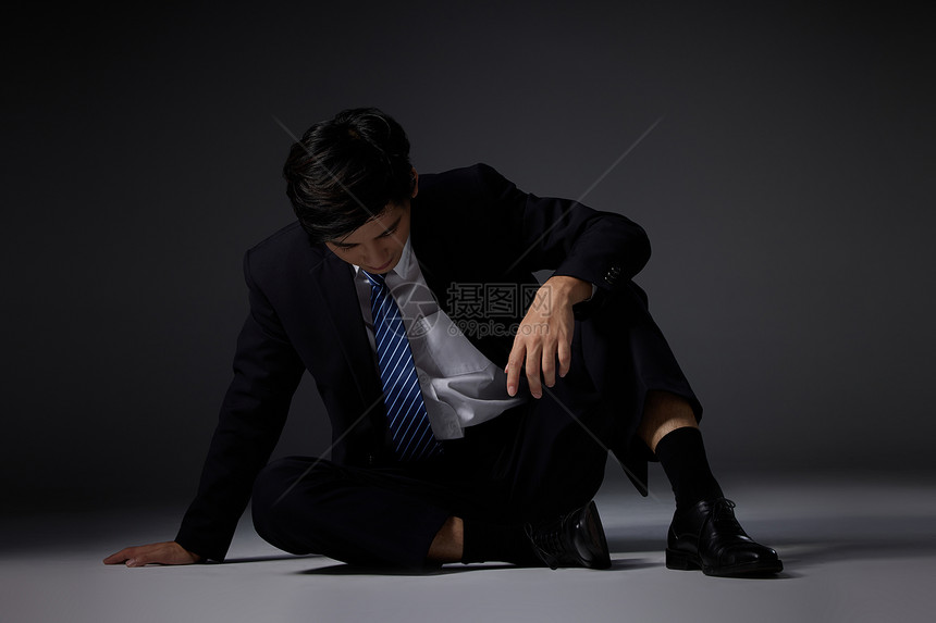 坐在地上悲伤的职场男性图片