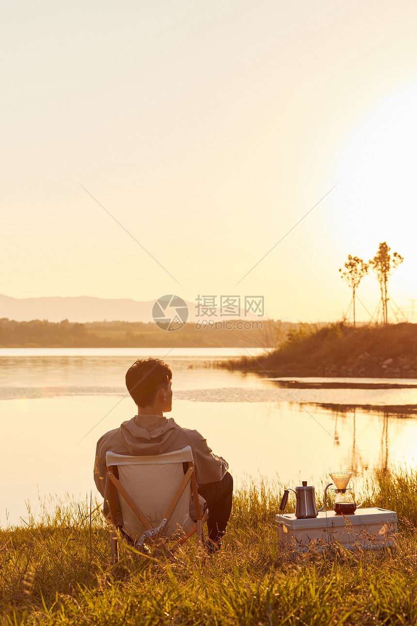 年轻男生坐在湖边看夕阳背影图片