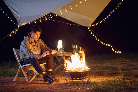 年轻男生户外野营烤火背景图片