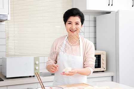 老人在厨房里展示包好的饺子图片