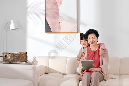 祖孙两人在客厅沙发上看平板电脑背景图片