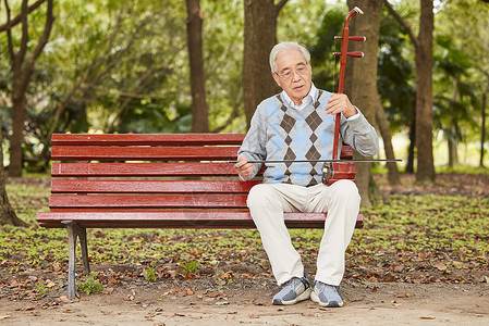 男性老人在长椅上拉二胡唱歌图片