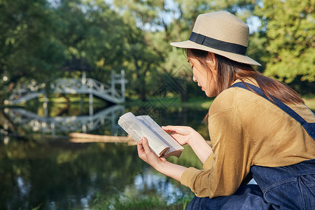 草帽青年美女大学生公园里郊游看书阅读背景