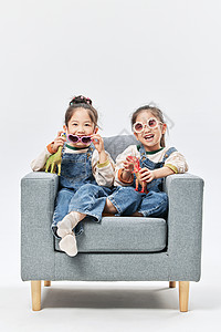 双胞胎小姐妹居家沙发上玩恐龙玩具高清图片