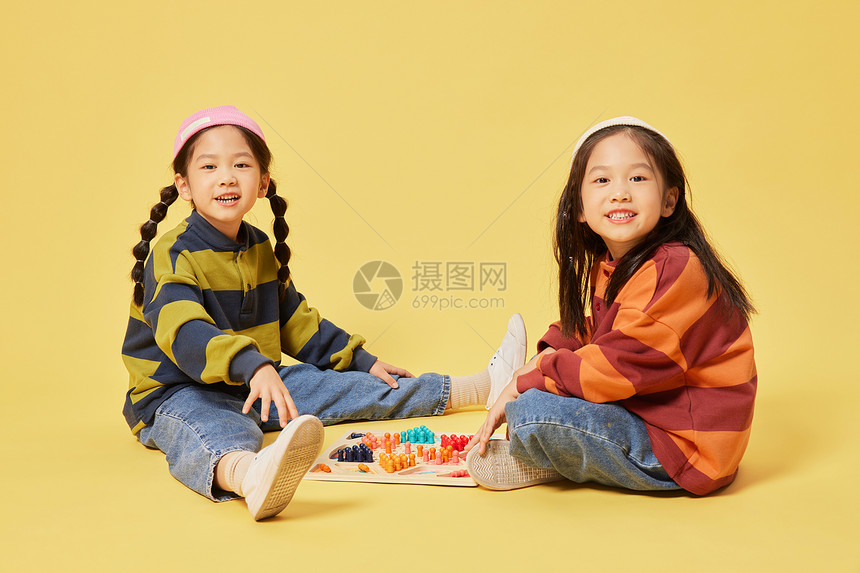 双胞胎小女孩姐妹坐着玩跳棋图片