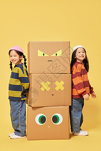 搞怪的人双胞胎小女孩躲在创意纸盒箱旁边背景