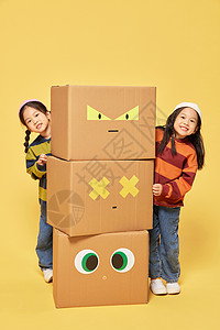 纸盒创意双胞胎小女孩躲在创意纸盒箱旁边背景