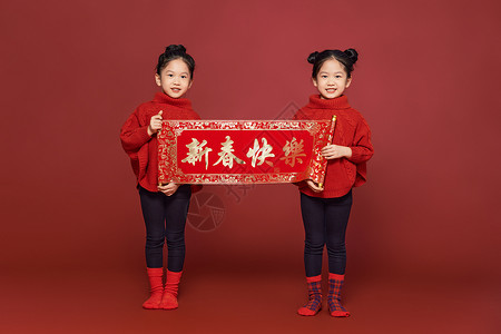 新年春节双胞胎女孩拿春联背景图片