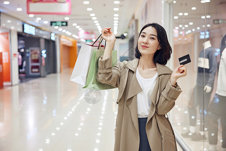 高兴购物年轻女性逛街购物展示信用卡背景