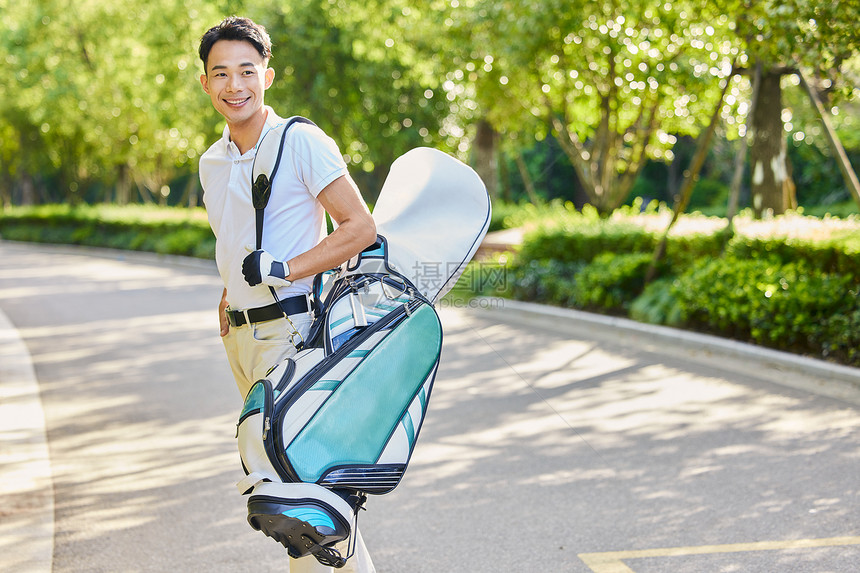 男性走路背着高尔夫球装备图片