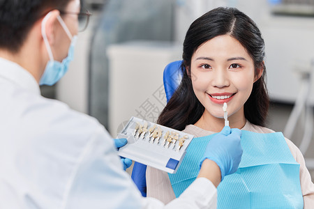 牙科技术员医生手拿牙齿给患者对比背景