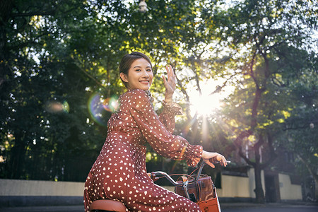 清新美女坐在自行车上回头打招呼图片