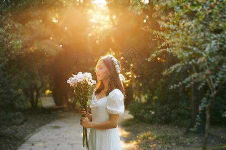 美女悠闲下午夕阳下拿着花的少女在微笑背景
