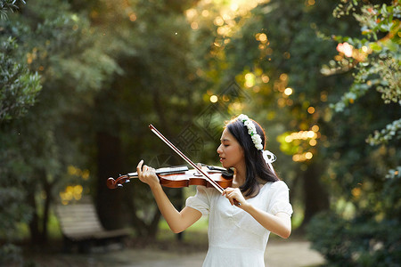 夕阳余晖中拉小提琴的少女高清图片