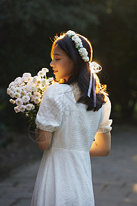 清新的连衣裙夕阳下拿着花的少女背景