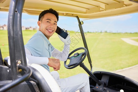 坐在在高尔夫球车上打电话的男性图片
