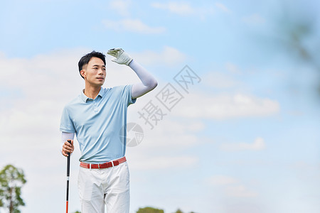男性手握高尔夫球杆眺望远方背景图片