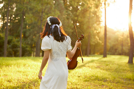 拿着吉他的少女夕阳余晖中拿着小提琴的少女背景