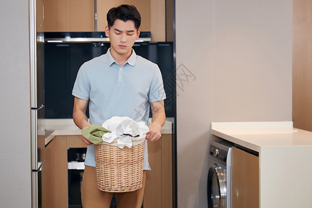 年轻男性在家里端着脏衣服高清图片