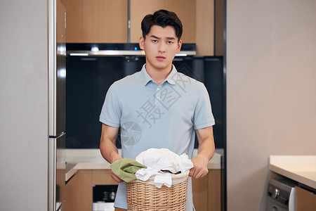 年轻男性居家洗衣服居家男性拿着一筐脏衣服背景