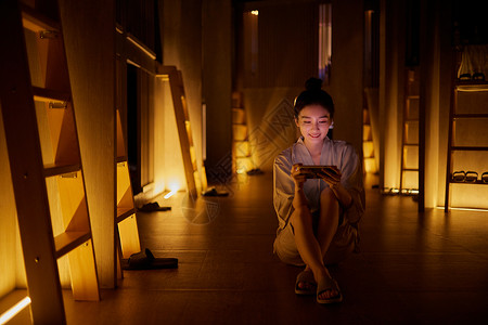 桑拿灯青年女性在汤泉馆休息区玩手机游戏背景