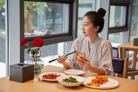 在前面吃饭青年美女在汤泉馆美食区吃饭玩手机背景