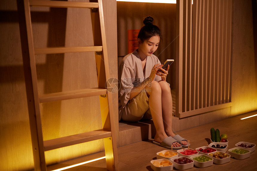 放松休息吃水果玩手机的青年女性图片
